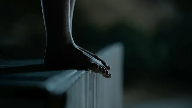 Kiernan Shipka with a bare foot visible at the edge of a seat in a film scene.