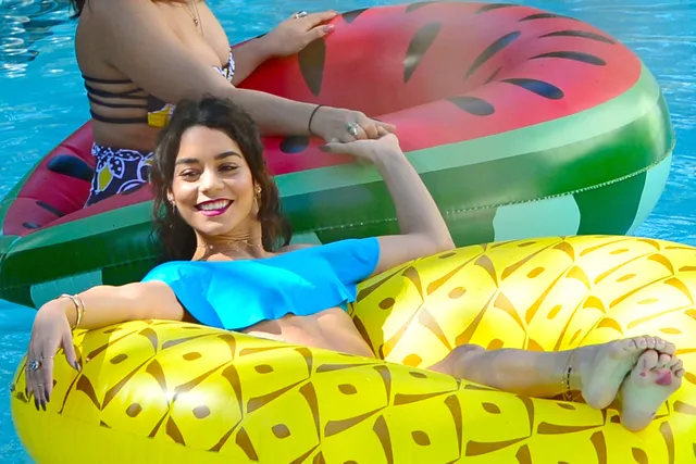 Vanessa Hudgens floating in a pool with bare soles facing forward.