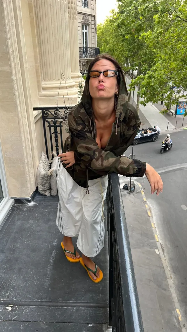 Adèle Exarchopoulos posing beside a street railing in flat shoes.