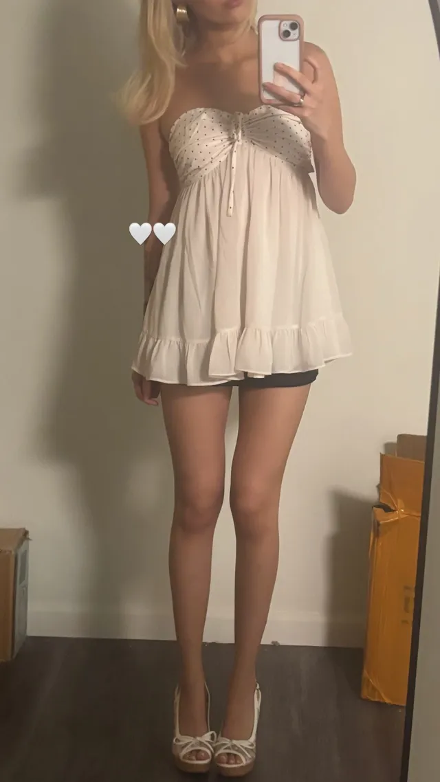 Grace VanderWaal taking a mirror selfie in a white dress and patterned heels.