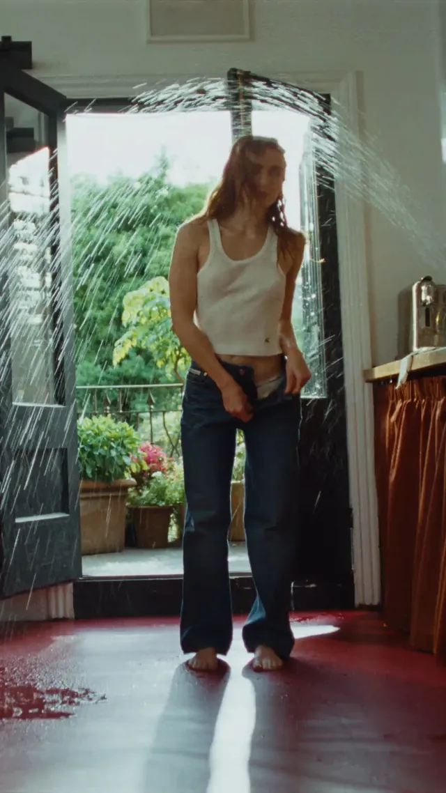 Sadie Sink standing barefoot near open glass doors.