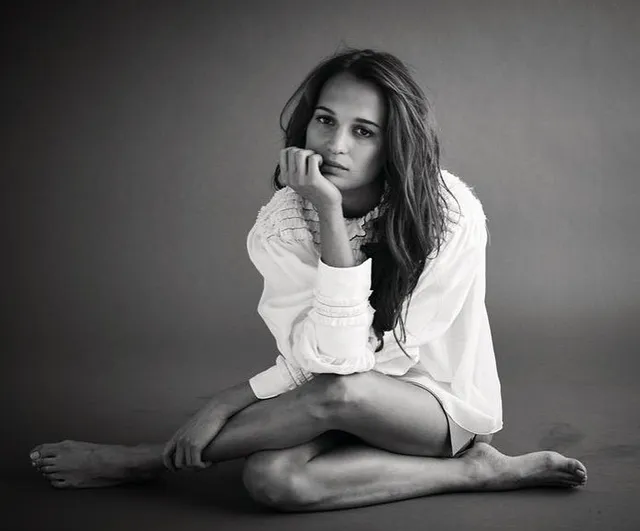 Alicia Vikander sitting on the floor in a monochrome portrait.