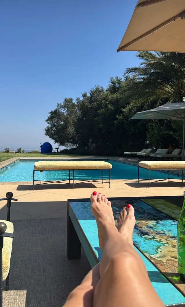 Heidi Klum crossing her bare legs while relaxing beside a pool.