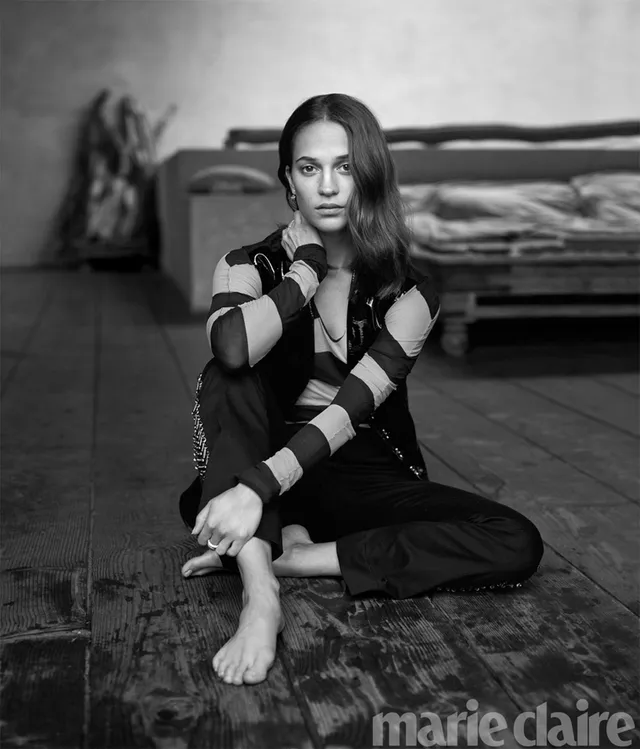 Alicia Vikander sitting on a floor in a monochrome fashion portrait.
