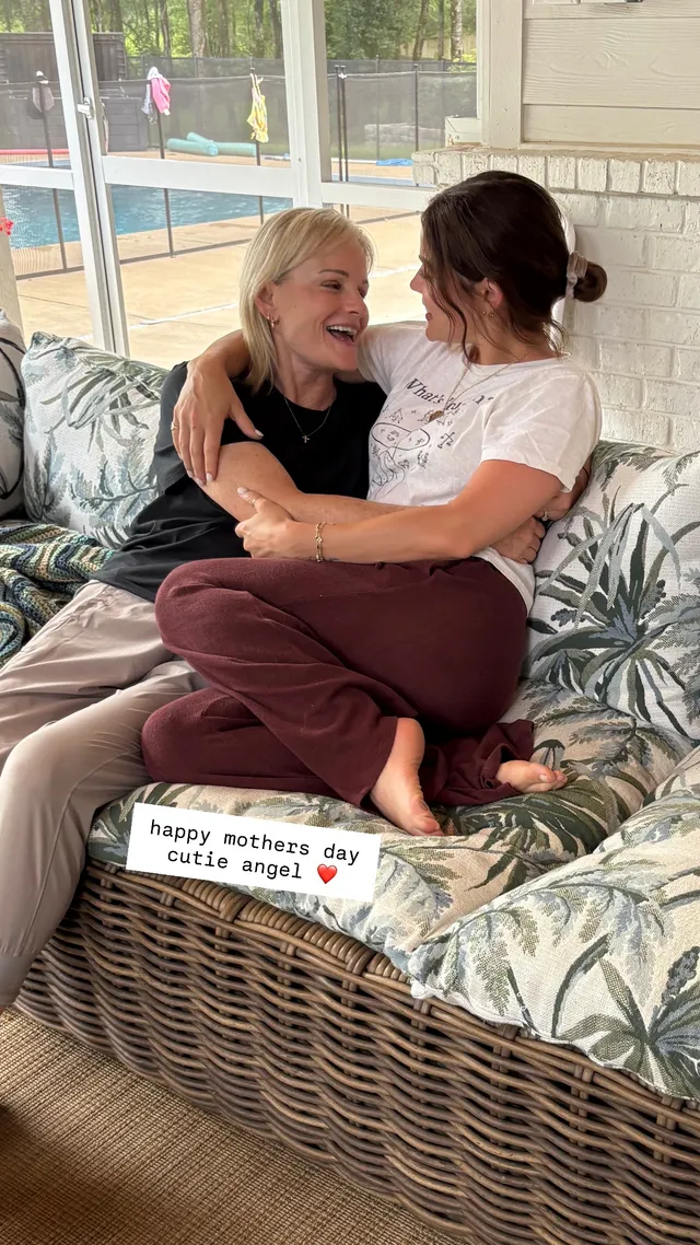 Lucy Hale sitting cross-legged with a companion on a patio sofa.