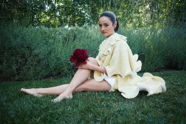 Chase Sui Wonders sitting barefoot on grass in a pale dress.