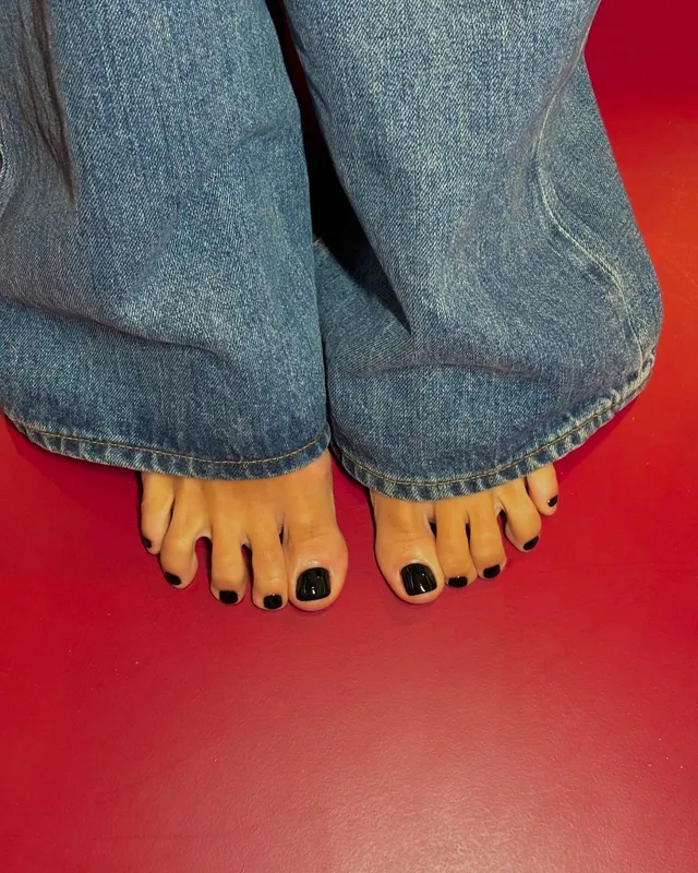 Lily Allen standing barefoot on a red carpet in jeans.