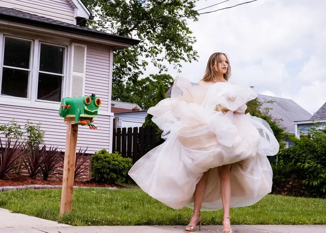 Halston Sage wearing a voluminous white dress and pale heels outdoors.