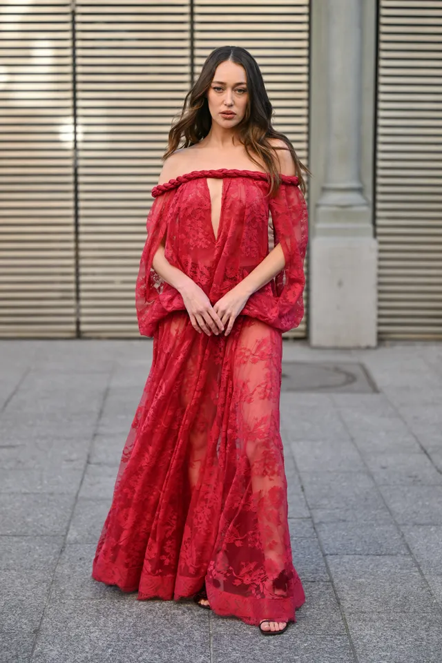 Alycia Debnam-Carey posing outside a venue in a long red dress.
