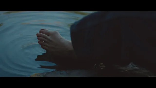 Chloë Grace Moretz with bare soles visible in a dimly lit screen image.