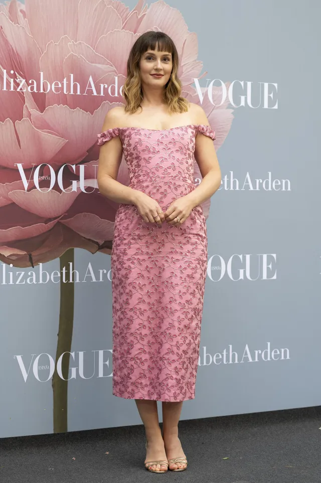 Leighton Meester posing at an event in a pink patterned dress.