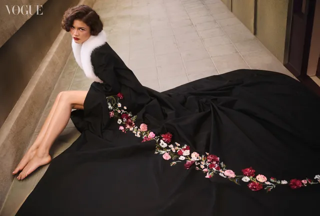 Zendaya: seated barefoot beside a trailing black embroidered dress.