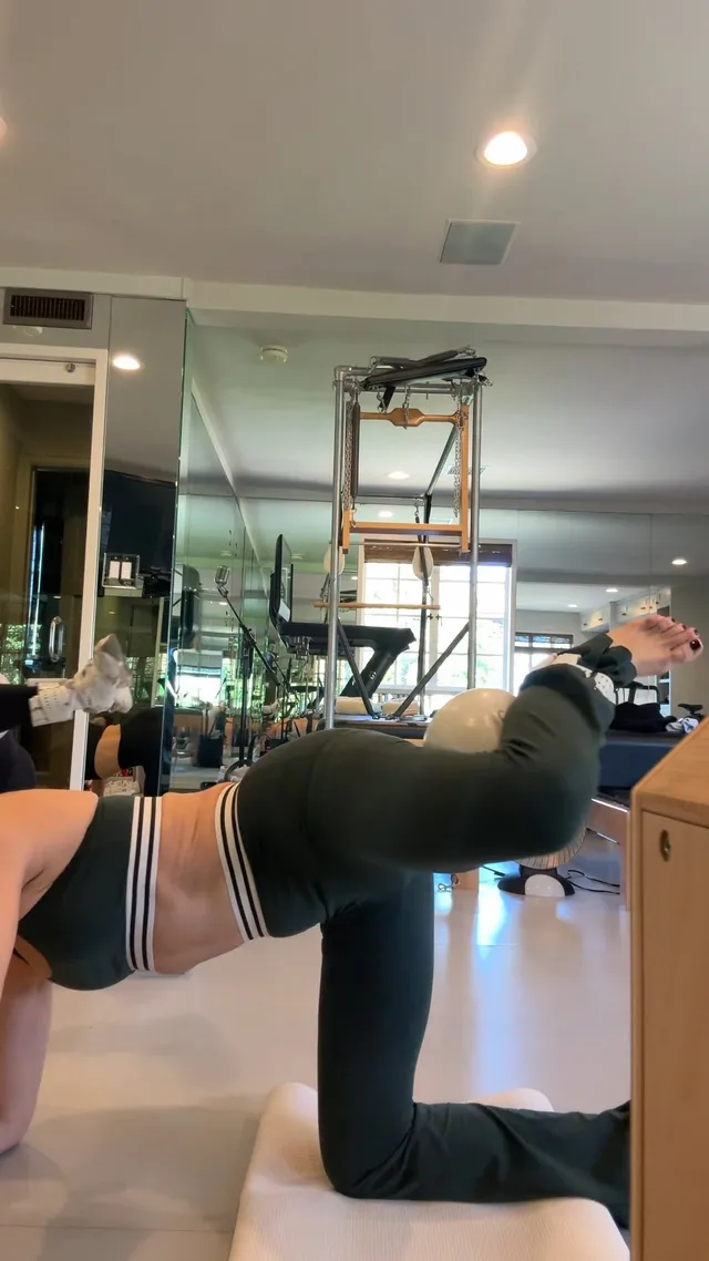 Kate Hudson stretching on exercise equipment in dark socks.