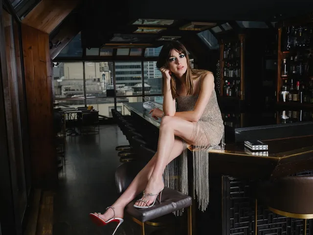 Daisy Edgar-Jones seated on a dark bench in a fringed dress.