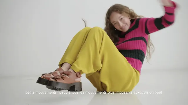Havana Rose Liu sitting in a striped top and brown platform sandals.