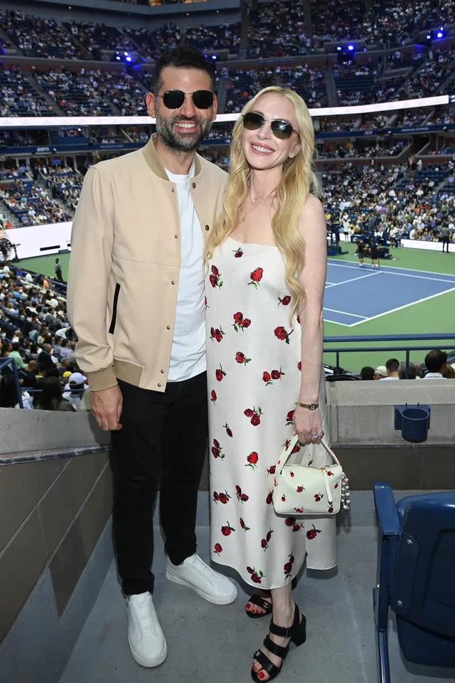 Lindsay Lohan posing with a companion at a tennis event.