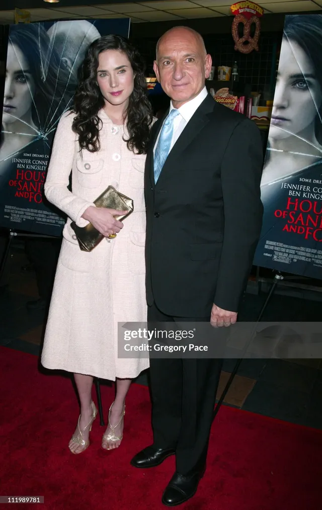 Jennifer Connelly posing with a companion in a cream coat.