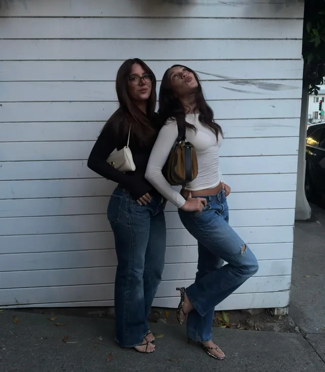 Mackenzie Ziegler posing with a friend in jeans and strappy heels.