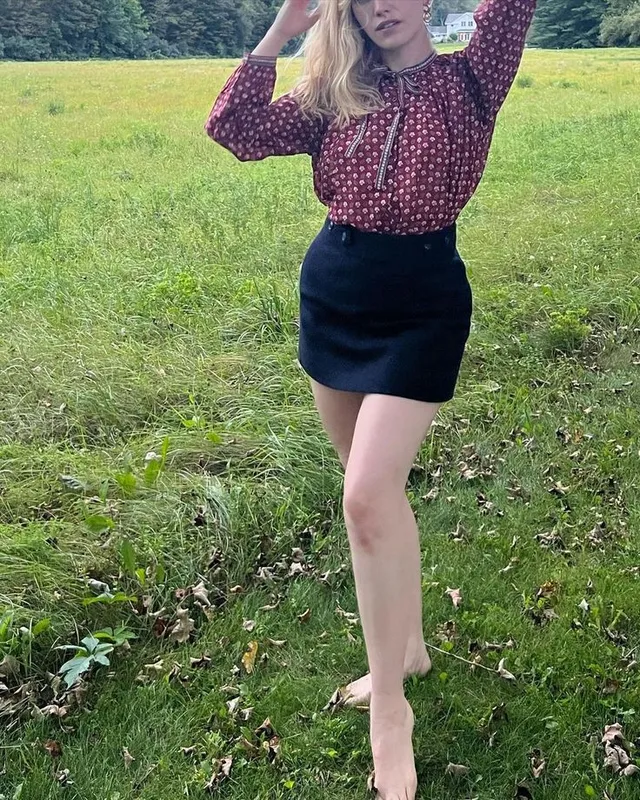 Victoria Pedretti standing outdoors in a patterned blouse and dark skirt.
