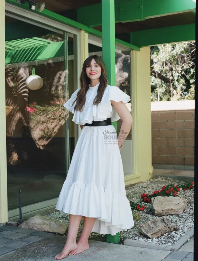 Elizabeth Olsen standing barefoot beside a green porch.