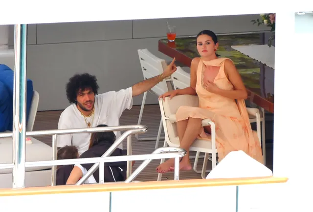 Selena Gomez sitting on a boat in a peach outfit.