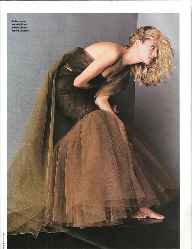 Uma Thurman posing barefoot in a brown dress.