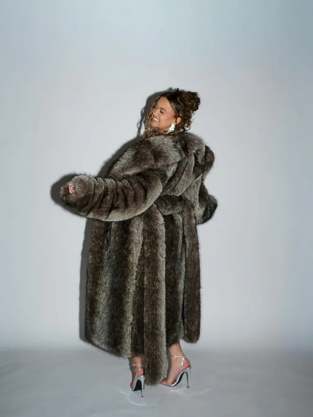 Madison Bailey posing in a long fur coat and clear heels.