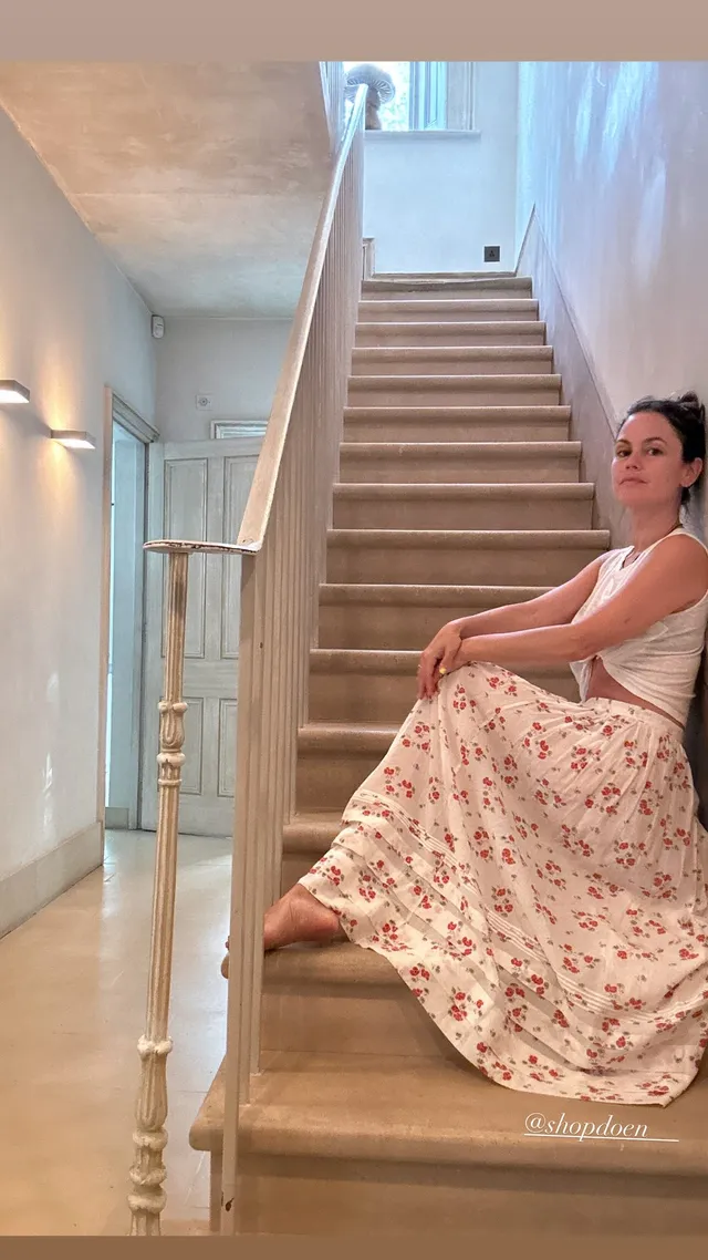 Rachel Bilson sitting on stairs in a floral skirt.