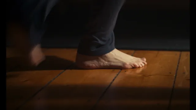 Eva Green a screen detail of a bare foot on a wooden floor.