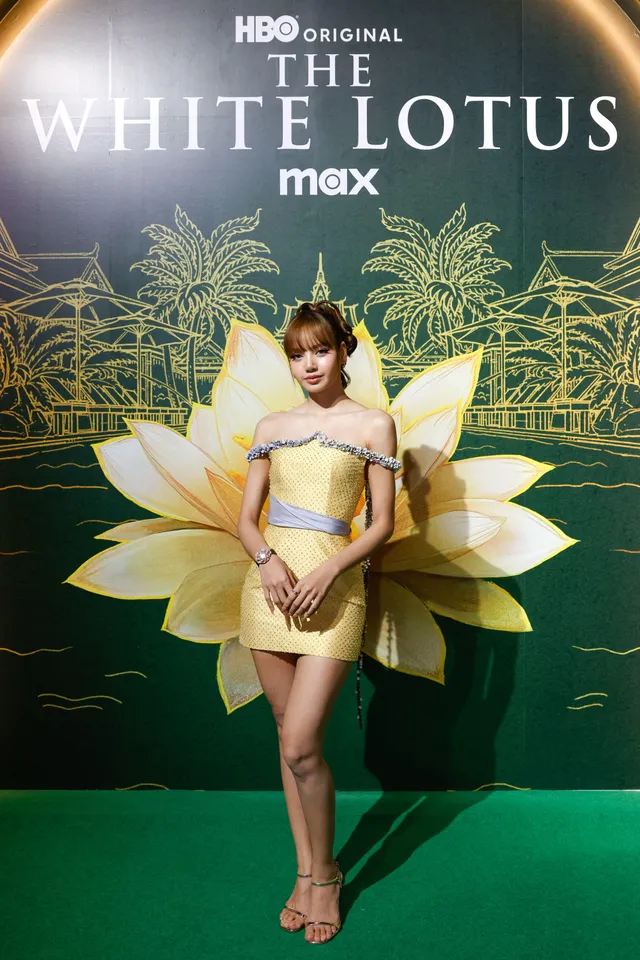 Lisa (Lalisa Manobal) wearing pale heels and a yellow outfit against a television-event backdrop.