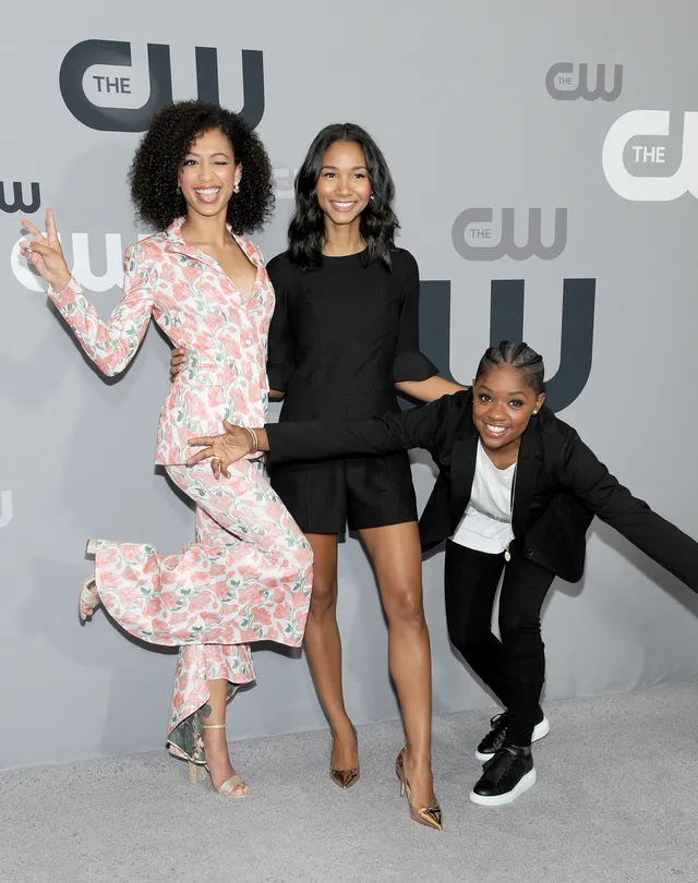 Samantha Logan posing with fellow performers in a floral suit and heels.