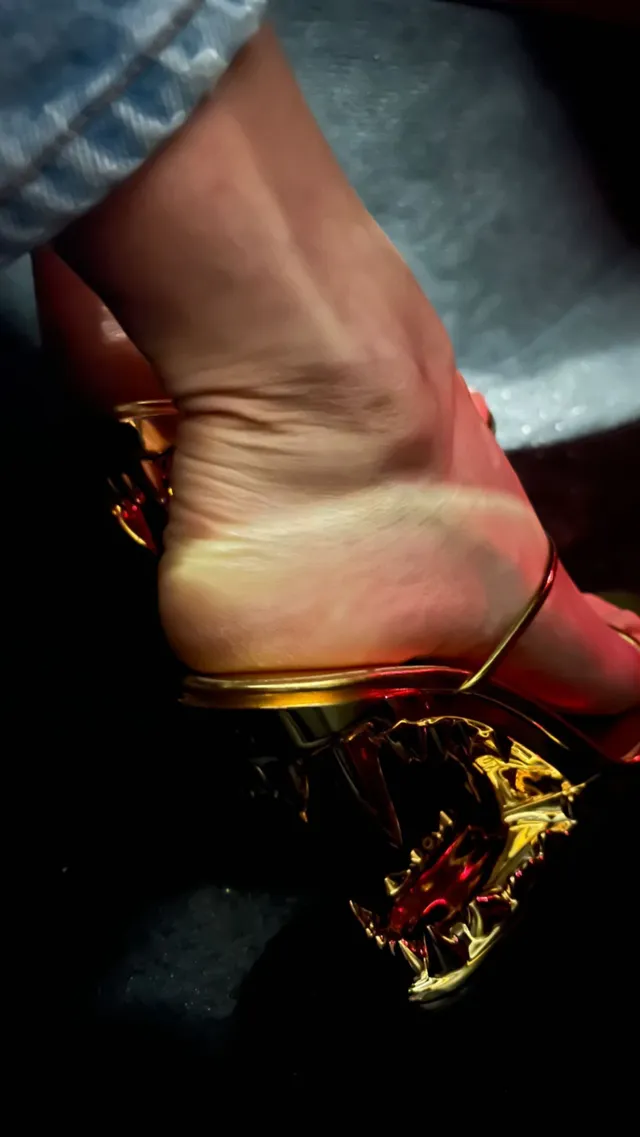 María Pedraza shown in a close-up wearing a decorative gold heel.