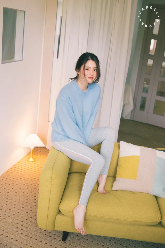 Han So-hee sitting barefoot on a yellow sofa.