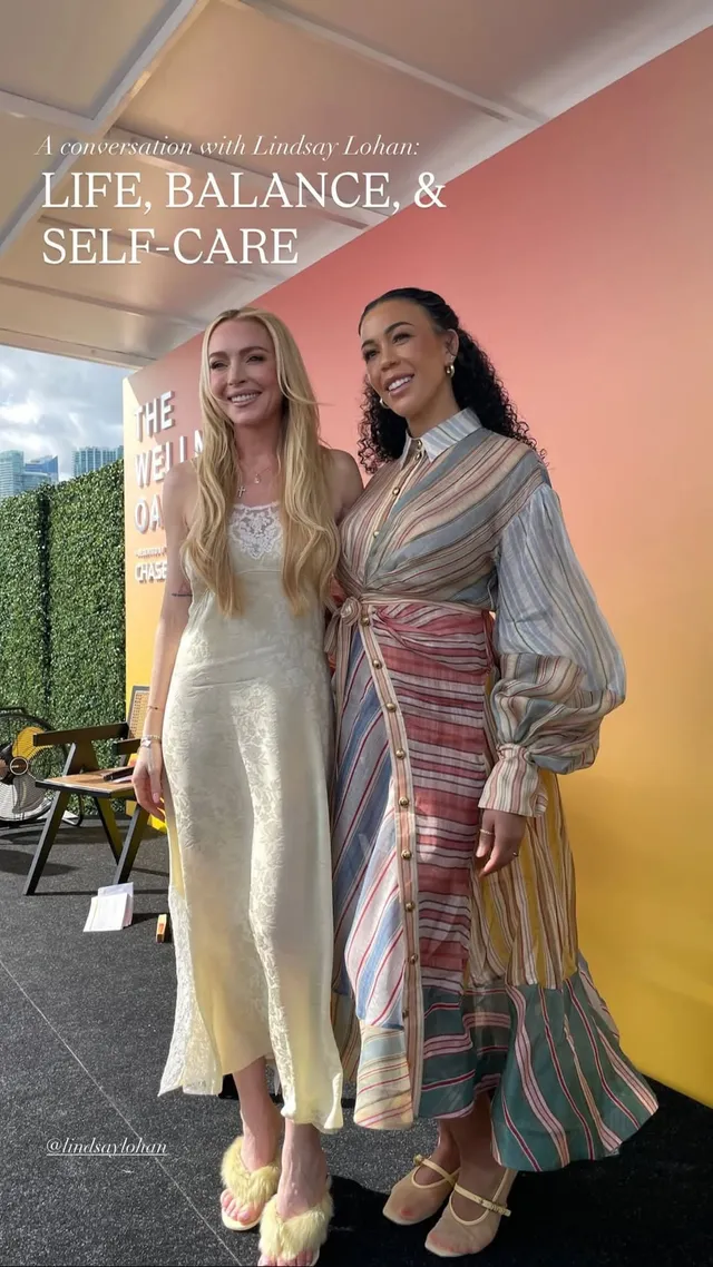 Lindsay Lohan posing in a white dress beside another woman.