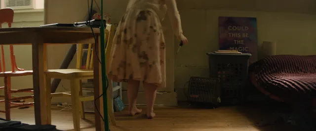 Dove Cameron standing in blue heels beneath a patterned dress.