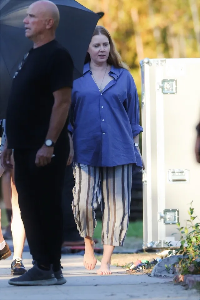 Amy Adams standing outdoors during a production in casual clothing.