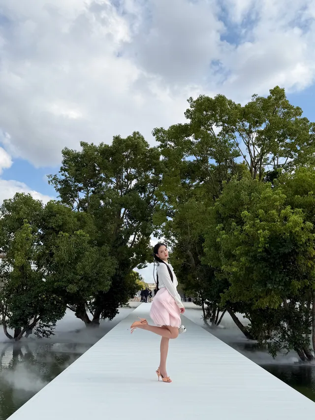 Jisoo posing in pale embellished heels beside a garden walkway.