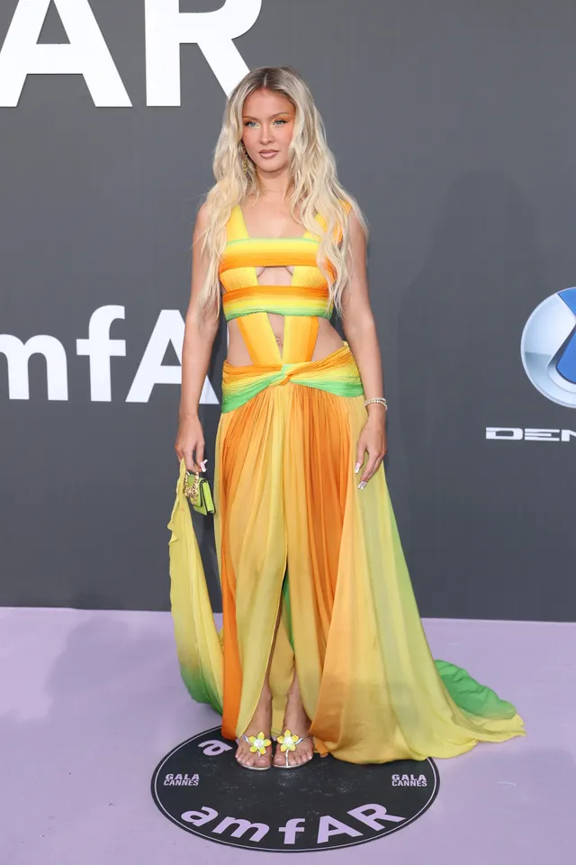 Zara Larsson standing at an event in a colourful gown and yellow heels.