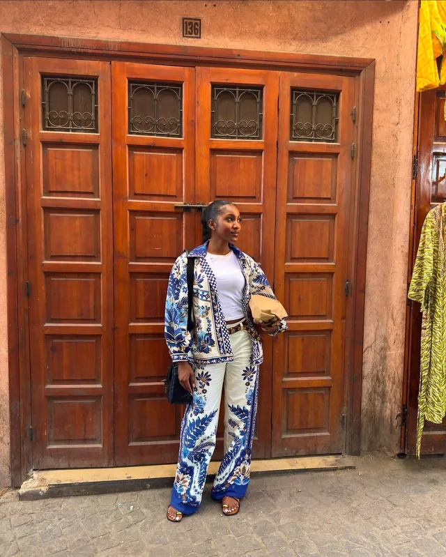 Carlacia Grant wearing a patterned trouser suit and blue heels outside a doorway.