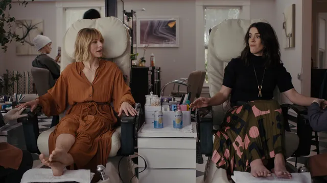 Kristen Bell sitting barefoot at a pedicure station indoors.