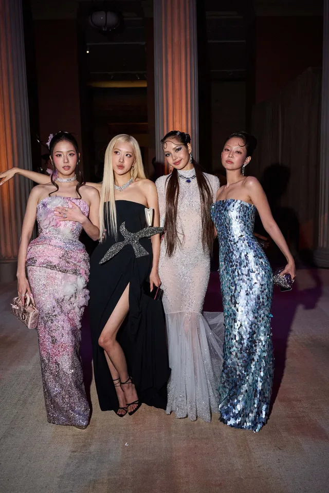 Rosé posing with other guests in a black gown and heeled sandals.
