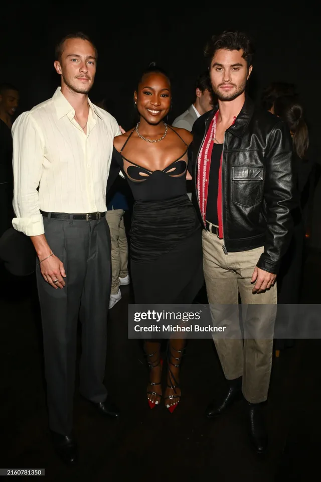 Carlacia Grant posing with two men in a black dress and colorful heels.