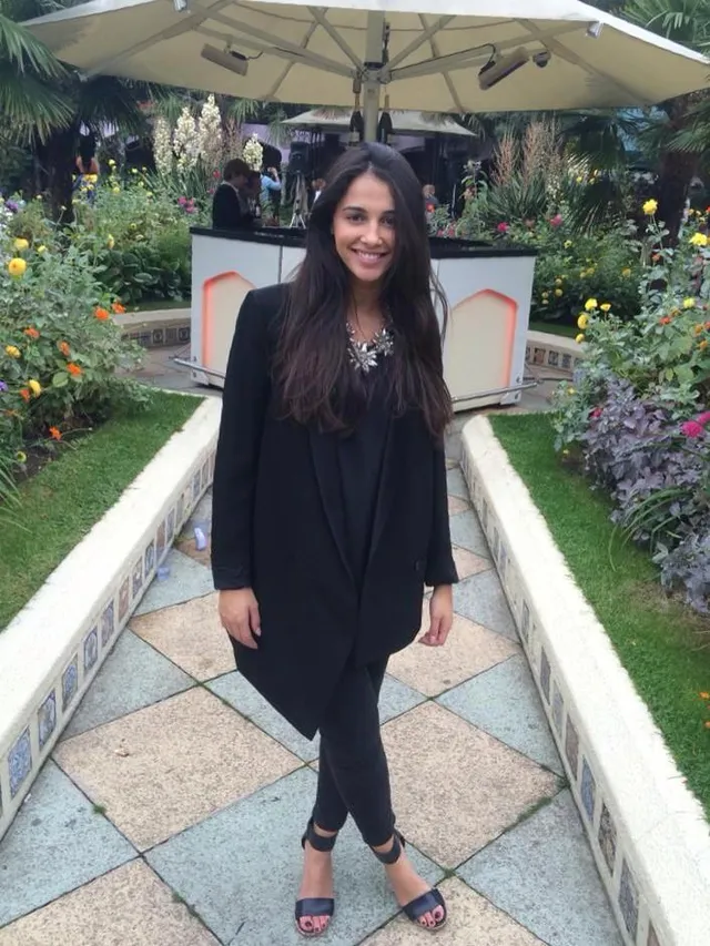 Naomi Scott standing barefoot outdoors in a dark outfit.