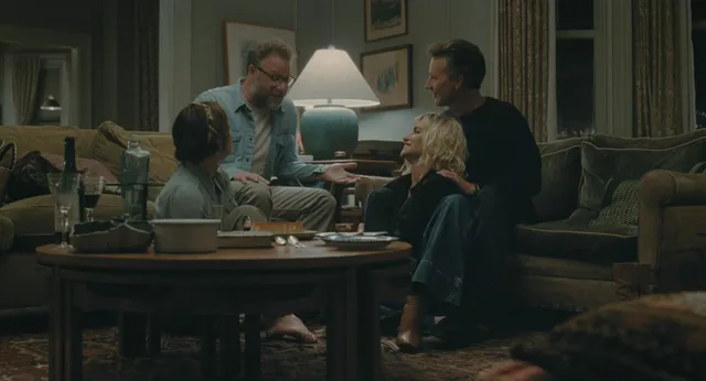Olivia Wilde sitting around a table with other people in a film scene.