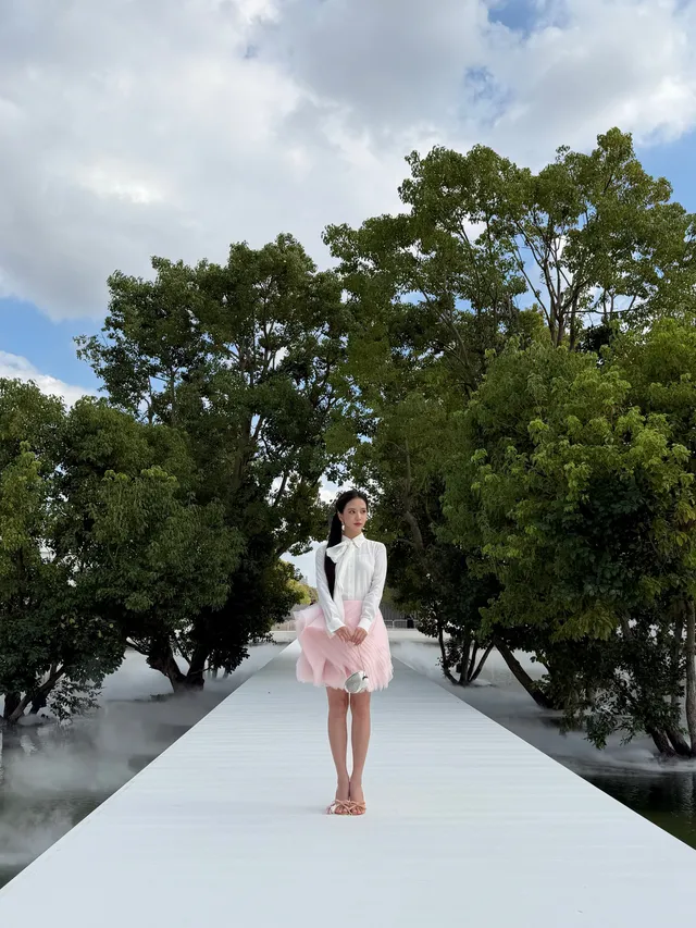 Jisoo standing in pale embellished heels at the end of a garden walkway.