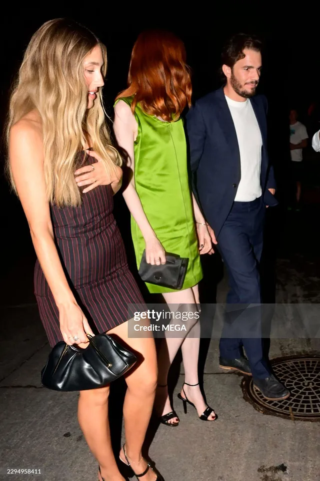 Karen Gillan standing beside other people wearing a green dress and black heels.