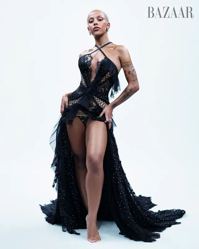 Doja Cat posing barefoot in a black dress in a magazine portrait.