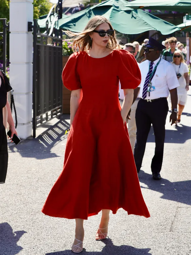 Maria Sharapova walking outdoors in heeled sandals and a red dress.
