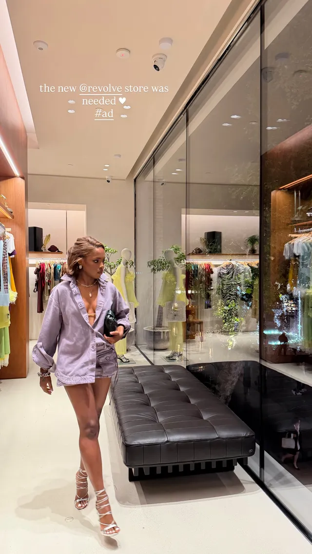 Ryan Destiny walking through a hotel lobby in a lavender outfit and silver heels.