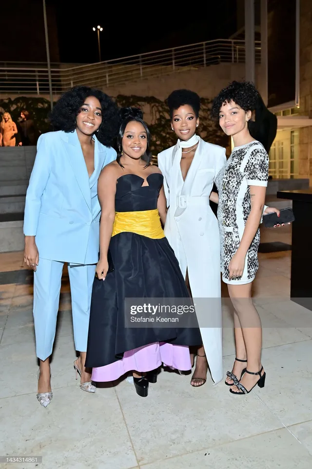 Whitney Peak posing with guests in a short patterned dress and black heels.
